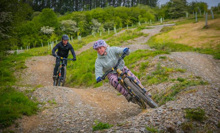 Action shot of a female rider railing a berm, with a huge smile on her face